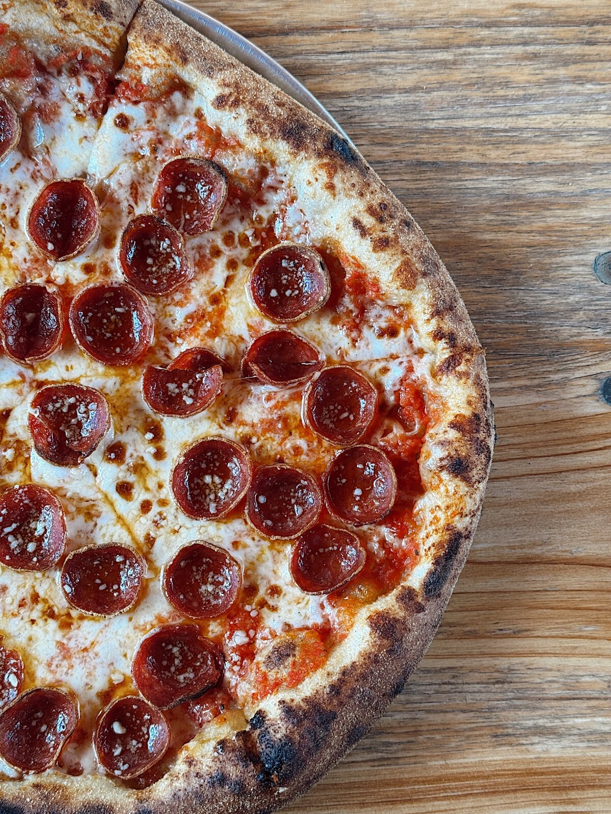 Fresh pepperoni pizza photographed on a rustic table