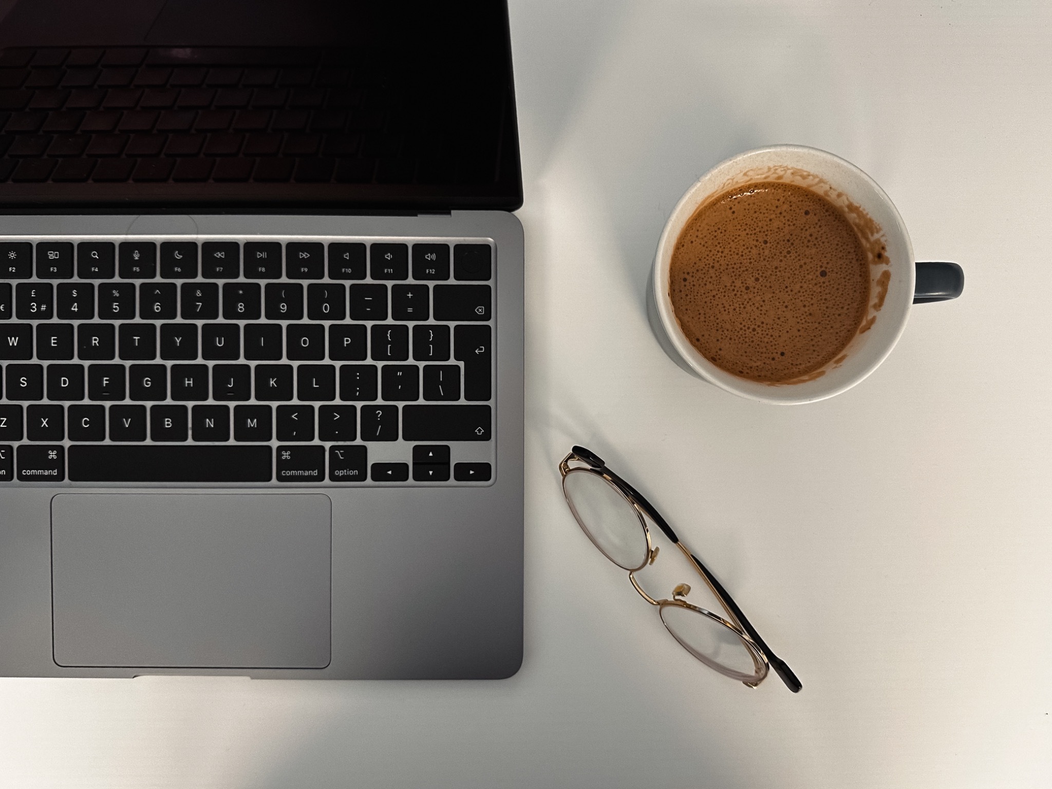 Open laptop, glasses and coffee on a Sunday & Company workspace