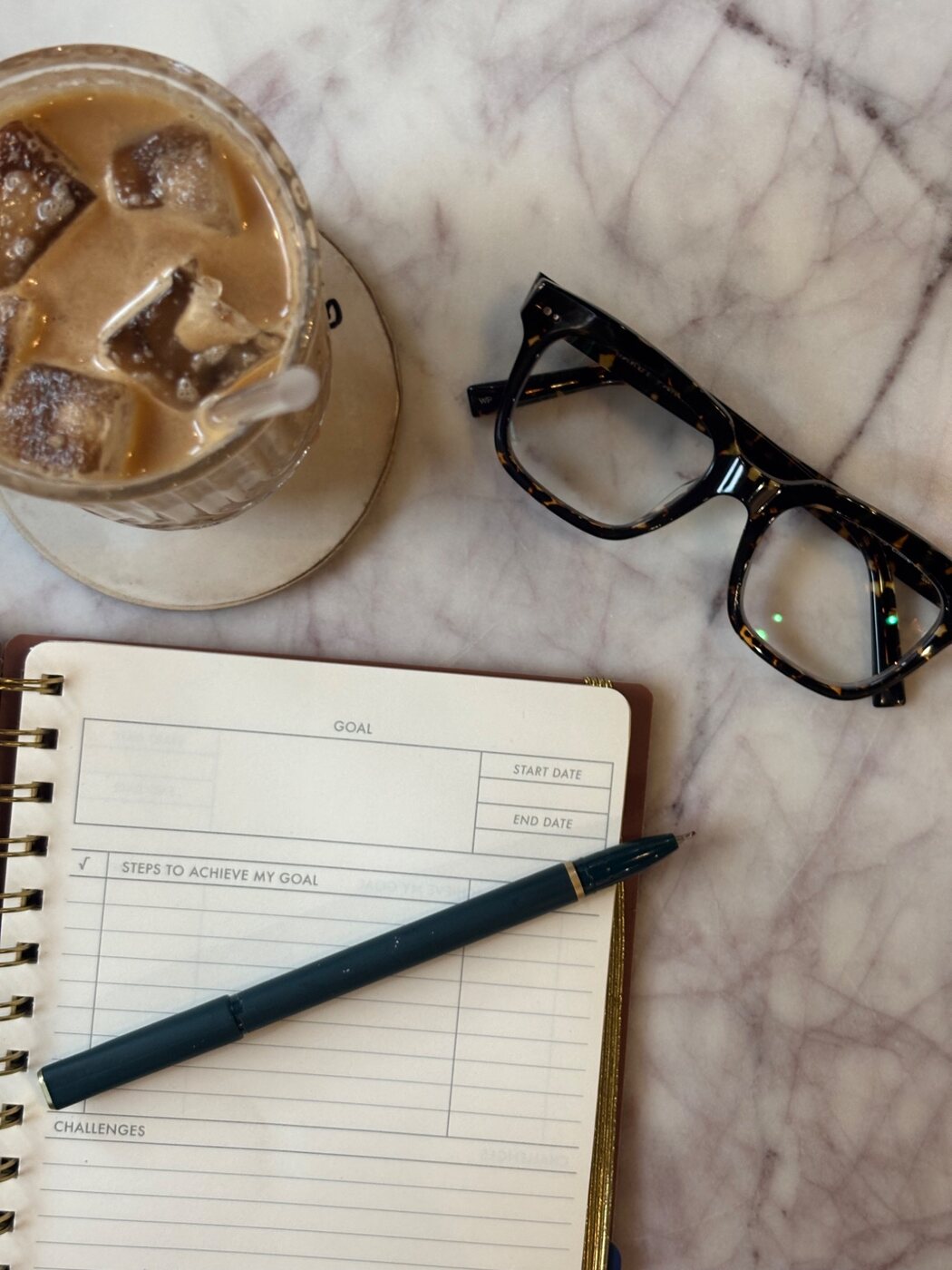 Planner, glasses and iced coffee